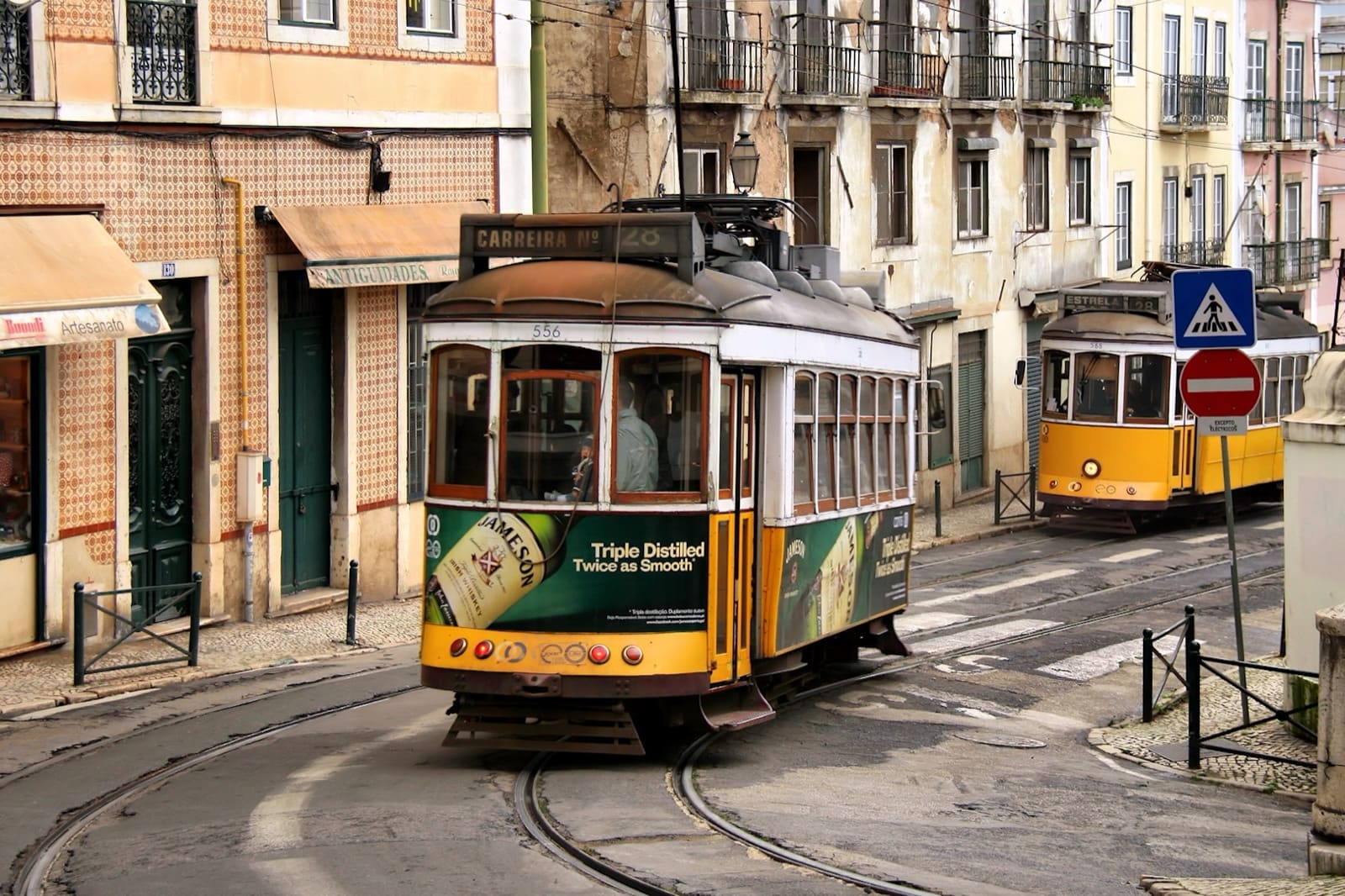 Two yellow heritage trams passing on a narrow Lisbon street